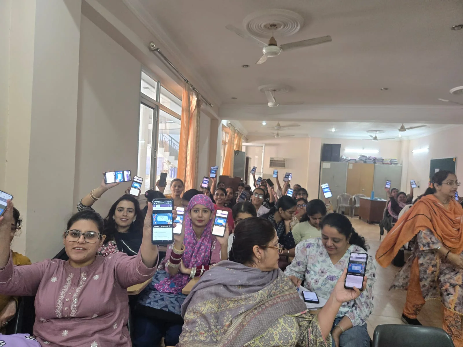 Women at a Passport to Earning session holding up phones showing their learning screens